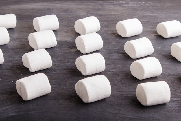 Set marshmallows na czarnym drewnianym tle. geometryczny wzór.