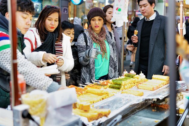 Seul, Korea Południowa - 14 marca 2016: Młode koreańskie dziewczyny kupują jedzenie uliczne na szaszłykach na targu Myeongdong w Seulu, w Korei Południowej