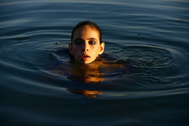 Sexy kobieta pozuje w wodzie. Lato. Zmysłowa dziewczyna portret lato. Piękna kobieta.