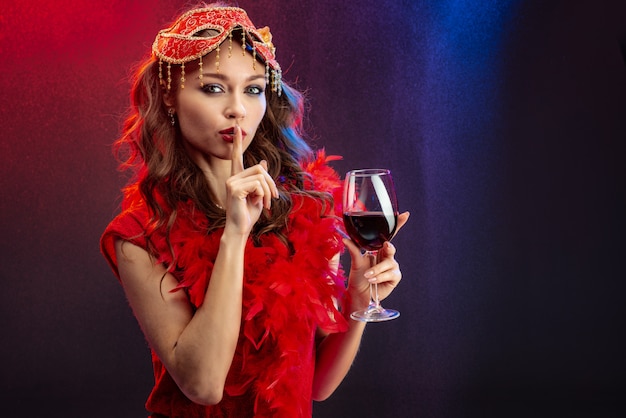 Zdjęcie sexy kobieta w czerwonym karnawałowe ubrania z podniesionym kieliszek wina