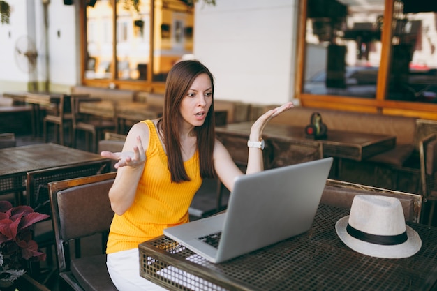 Sfrustrowana Kobieta W Kawiarni Na świeżym Powietrzu W Kawiarni Siedząc Przy Stole, Pracując Na Nowoczesnym Komputerze Typu Laptop, Restauracja W Czasie Wolnym