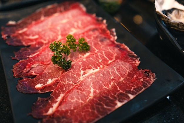 Shabu wołowe w plasterkach na czarnym talerzu w restauracji, japońska wołowina w plasterkach