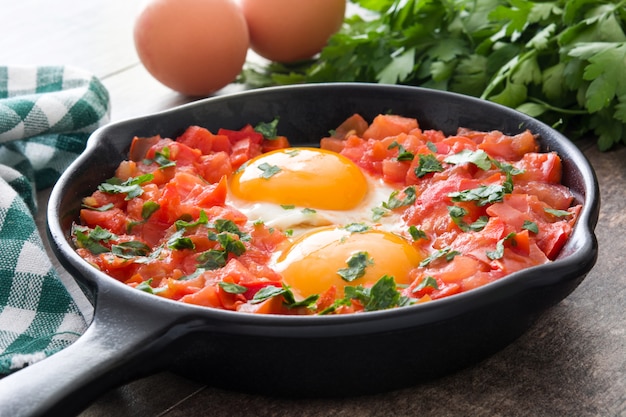 Shakshuka w żelaznej patelni na drewnianym stole Typowe jedzenie w Izraelu.