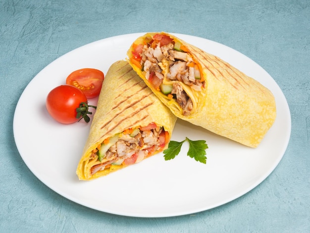 Shawarma z kurczakiem i warzywami w serowym chlebku pita na niebieskim tle