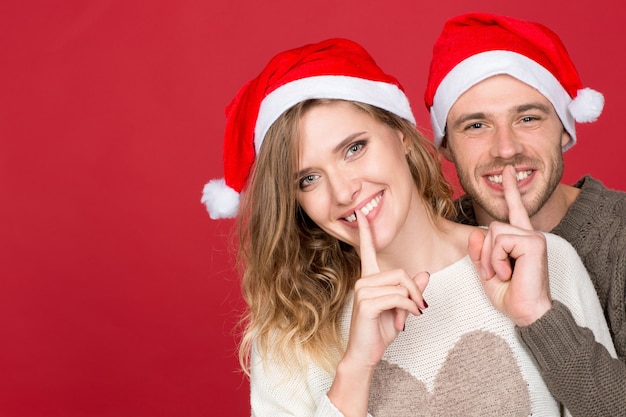 Shh Santa Jest Tutaj! Poziome Portret Młodej Pary Szczęśliwej Noszenia Czapek Bożego Narodzenia Dokonywania Gest Uciszenia