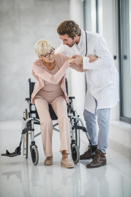 Shot of młody lekarz pomaga starszej pacjentki na wózku inwalidzkim.