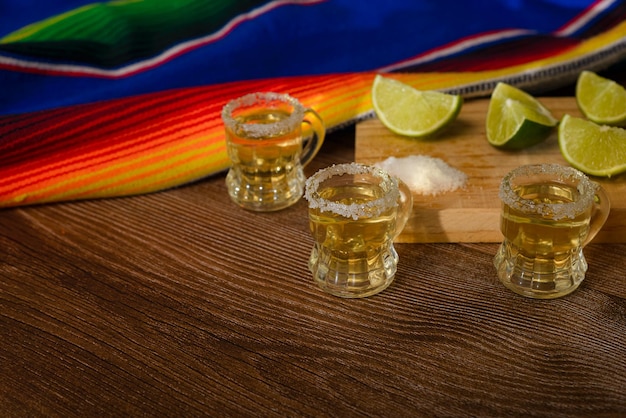Shoty tequili z solą i limonką na stole barowym Shoty tequili z typowymi meksykańskimi elementami