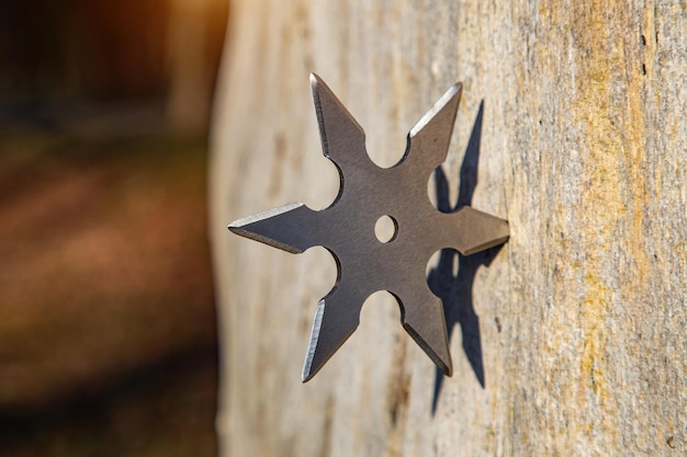 Shuriken gwiazda do rzucania tradycyjna japońska zimna broń ninja utknęła w drewnianym tle