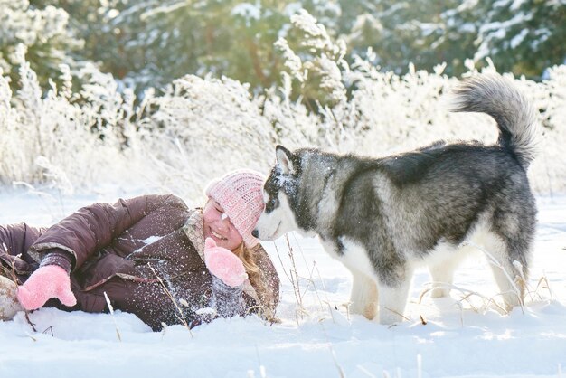 Siberian Husky pies i mała dziewczynka bawią się w śnieżnym zimowym lesie