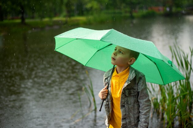 Siedmioletni chłopiec pod parasolem w letnim parku