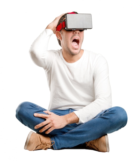 Siedzący młody człowiek, używając szklanki wirtualnej rzeczywistości