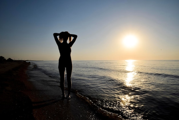 Silhoueta dziewczyny na zachodzie słońca nad morzem ciemna sylwetka na zachodzie morza Dziewczyna na plaży wieczorem