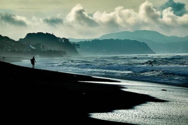 Zdjęcie silhueta osoby stojącej na brzegu morza przeciwko niebu