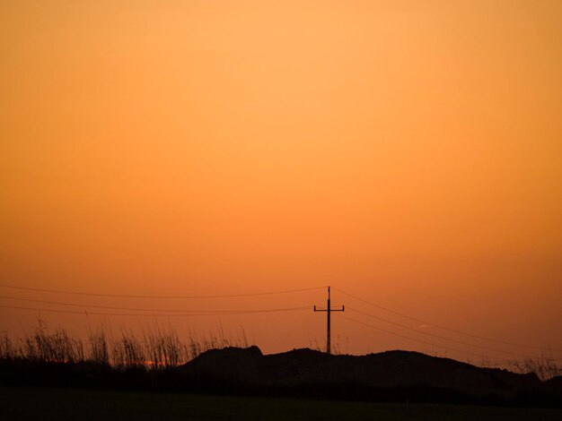 Zdjęcie silhueta słupów elektrycznych na tle romantycznego nieba przy zachodzie słońca