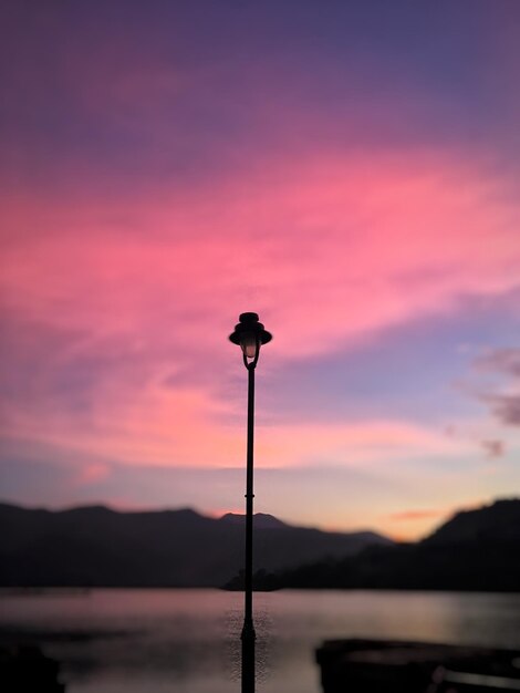 Zdjęcie silhueta światła ulicznego przy jeziorze na tle romantycznego nieba przy zachodzie słońca