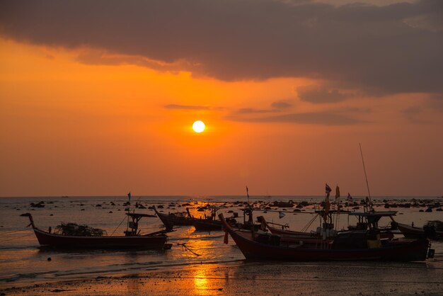 Zdjęcie silhuetowe łodzie zacumowane na morzu na pomarańczowym niebie