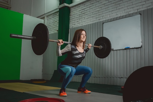 Silna kobieta podnosząca sztangę w ramach rutyny ćwiczeń crossfit