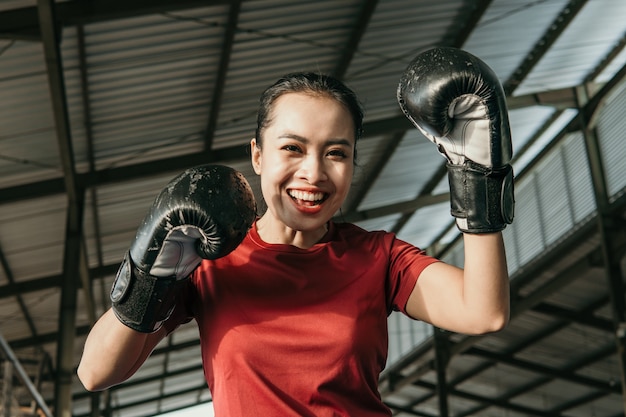 Silna młoda kobieta w stroju bokserskim wykonuje ruch uderzenia na boisku treningowym
