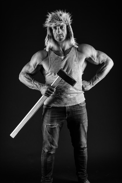 Zdjęcie silny kowal trzyma młotek w mięśniowych ramionach biceps triceps w zwykłym ubraniu czarny tło trening