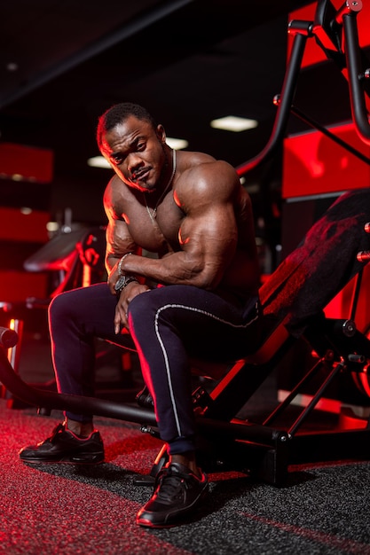 Silny kulturysta z nagim torsem odpoczywa po ciężkim treningu na siłowni Afroamerykański sportowiec o silnych, umięśnionych dłoniach