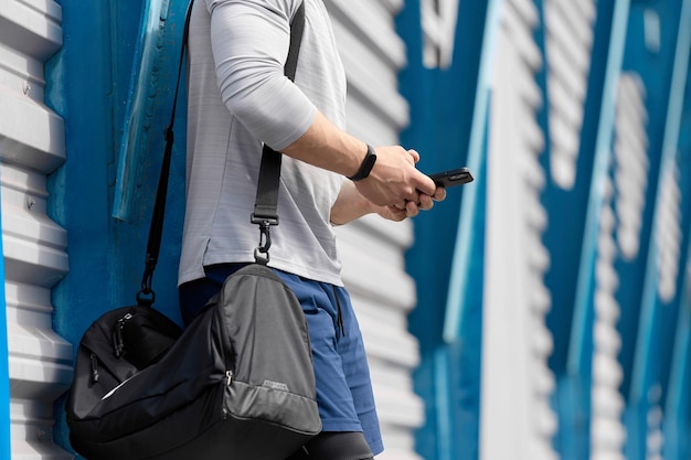 Silny mężczyzna z torbą sportową przyszedł na stadion trzymając telefon komórkowy w dłoniach