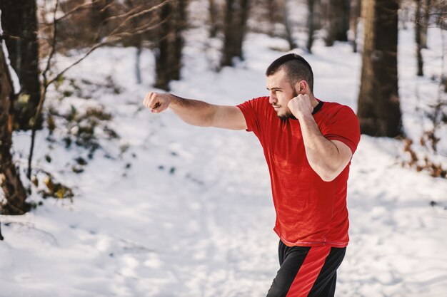 Silny muskularny sportowiec sparingowy na łonie natury w śnieżny zimowy dzień. Fitness zimą, sparingi, sporty