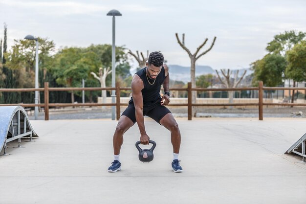 Silny sportowiec podnoszący kettlebell w parku