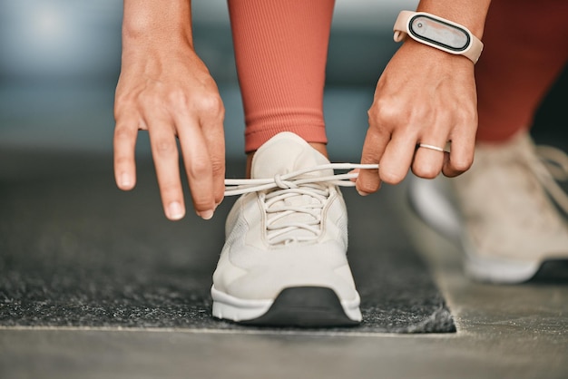 Siłownia lub ręce zawiązują buty, aby rozpocząć trening, ćwiczenia sportowe lub trening cardio z obuwiem do biegania Nogi wellness lub zdrowa dziewczyna z celami zaangażowania lub motywacją, gotowa do ćwiczeń