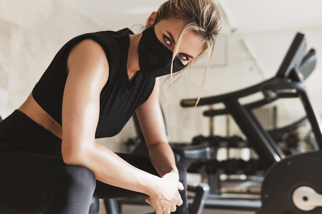 Siłownia Nowa Normalna. Młoda Kobieta Lekkoatletycznego Noszenie Maski Profilaktycznej Podczas Jej Treningu Fitness.