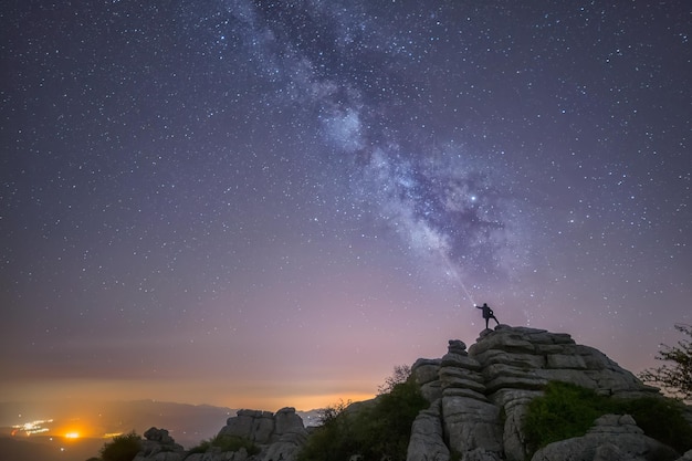 silueta humana con luz iluminando las estrellas sobre una roca cielo estrellado