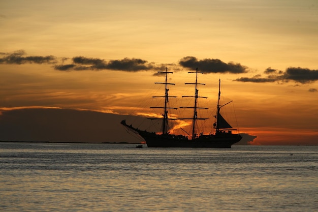 Zdjęcie silueta statku na morzu na tle nieba podczas zachodu słońca