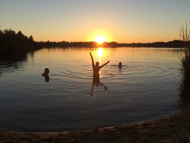 Zdjęcie siluetowe kaczki pływające w jeziorze na tle nieba podczas zachodu słońca