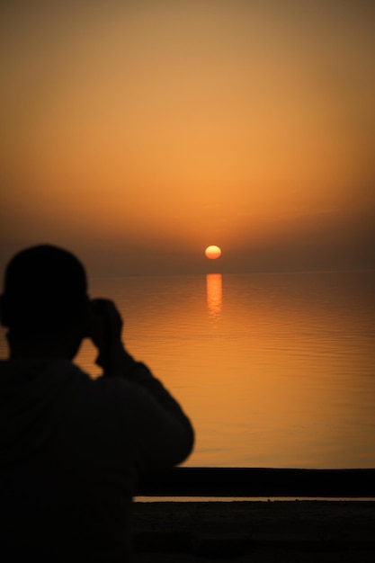 Siluweta człowieka na korytarzu przeciwko morzu i niebu podczas zachodu słońca