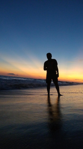Zdjęcie siluweta człowieka stojącego na plaży