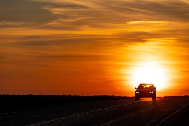 Zdjęcie siluweta samochodu na drodze na tle słońca samochód jeździ po autostradzie podczas zachodu słońca koncepcja podróży i wolności