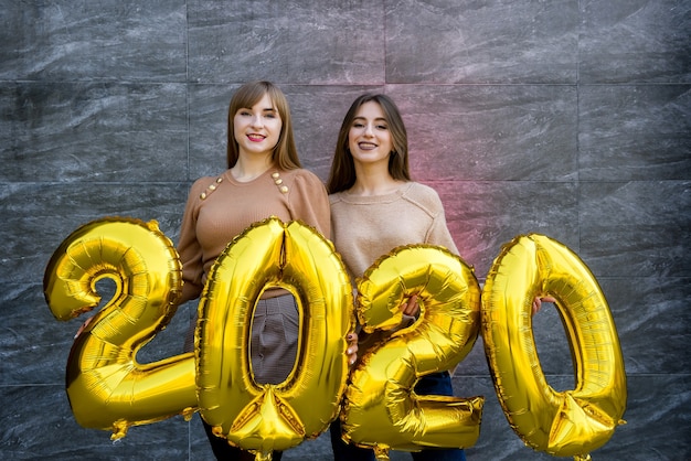 Siostry świętują Nowy Rok 2020. Trzymają Złote Balony Na Imprezie