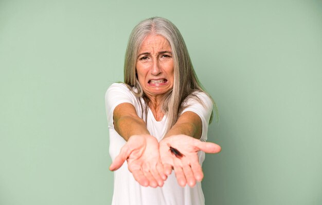 Siwe włosy starsza ładna kobieta trzymająca owada palcami