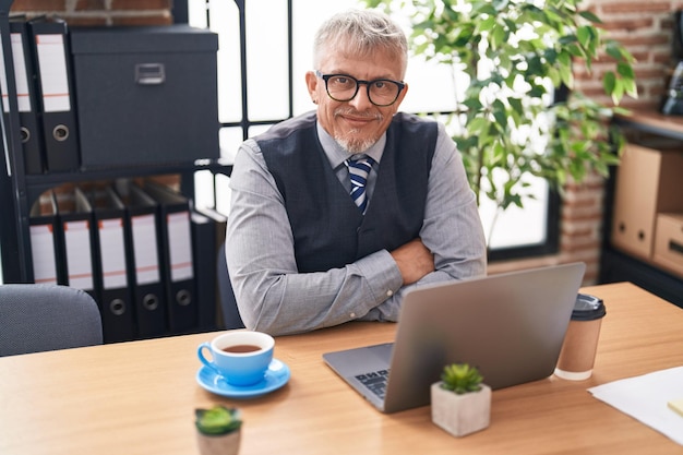 Siwowłosy mężczyzna w średnim wieku, pracownik biznesowy korzystający z laptopa pracującego w biurze