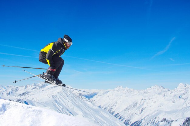 Zdjęcie skaczący narciarz w skoku z alpejskimi wysokimi górami