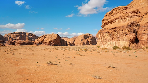 Skaliste masywy na pustyni z czerwonym piaskiem, jasne błękitne niebo w tle - typowa sceneria w Wadi Rum, Jordania.