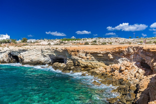 Skalisty brzeg, czysta turkusowa woda morska i niebieskie niebo w Ayia-Napa, Cypr, park rzeźb.