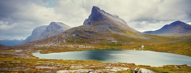 Skalisty brzeg górskiego jeziora w deszczowy jesienny poranek Piękna natura Norwegii
