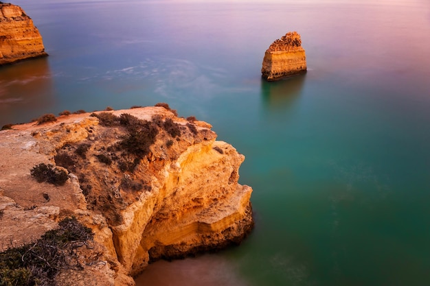 Skały Na Brzegu Oceanu Atlantyckiego O Zachodzie Słońca W Algarve, Portugalia. Strzał Z Długim Czasem Naświetlania. Piękny Pejzaż Morski