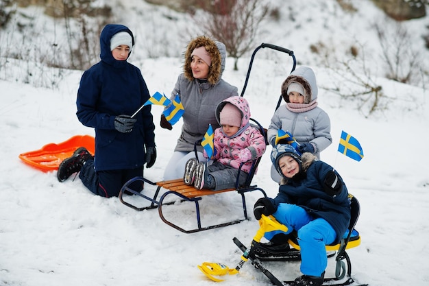 Skandynawska rodzina z flagą Szwecji w zimowym szwedzkim krajobrazie