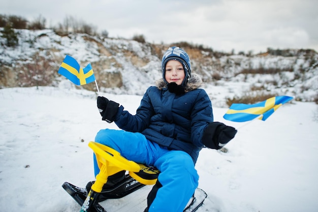Skandynawski chłopiec z flagą Szwecji w zimowym szwedzkim krajobrazie