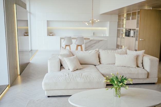 Skandynawski styl jasny klasyczny nowoczesny luksusowy salon jadalnia i kuchnia z drewnianymi, białymi, marmurowymi detalami, nowe stylowe meble, wygodna sofa rozkładana, minimalistyczny nordycki wystrój wnętrz.