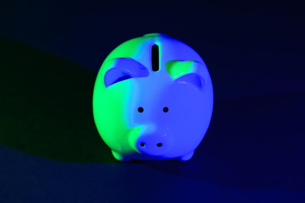 Zdjęcie skarbonka na ciemnym tle z podświetleniem greenblue koncepcja bankowa jasne neony na czarnym tle