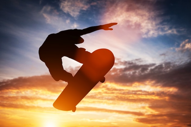 Skateboarder skoki o zachodzie słońca.