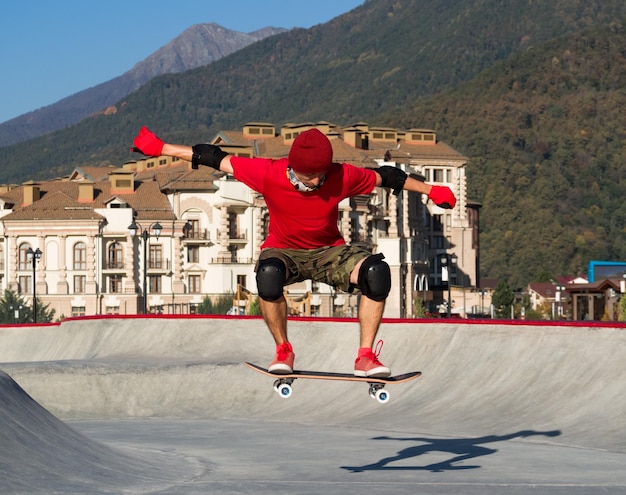 Zdjęcie skater skaczący na deskorolce w skateparku w letni słoneczny dzień