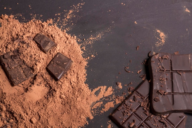 Skład batonów i kawałków różnej mlecznej i ciemnej czekolady tartego kakao na szarym tle widok z góry z bliska
